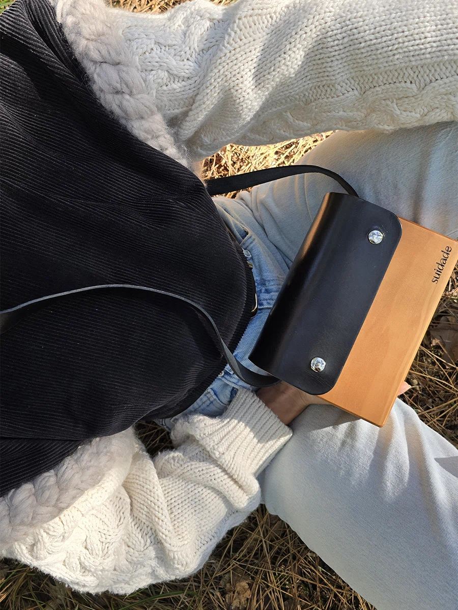 Bolso artesanal negro de madera y cuero Suidade con luz cálida del atardecer.